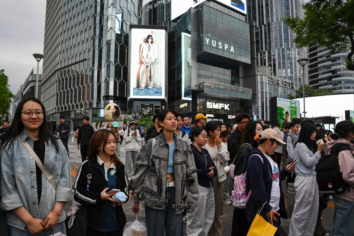 People wait to cross a road outside a shopping mall in Beijing. Expectations are high that China’s leaders will announce more measures to shore up the economy amid an intensifying trade war with the United States. Photo: AFP