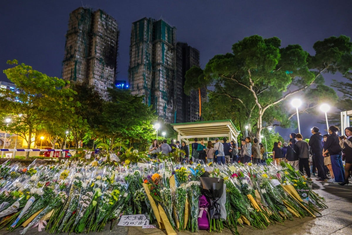 Floral tributes continue to grow near the scene of the tragedy in Tai Po, with Wang Fuk Court in the background. Photo: Edmond So