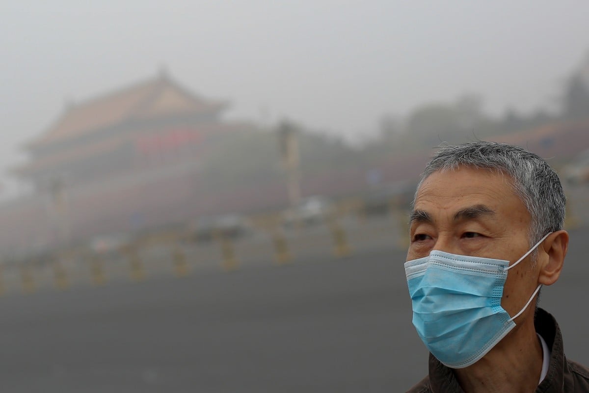 A man wears a mask as Tiananmen Square is shrouded in haze after a yellow alert was issued for smog in Beijing on November 14, 2018. Photo: Reuters