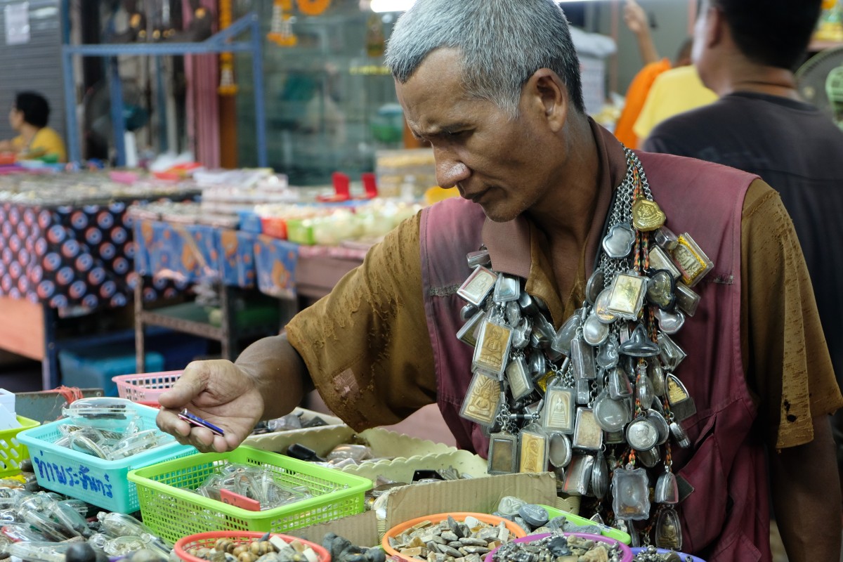 His clothes old and frayed, Kob Ladkrabang, a Thai amulet enthusiast, looks for a new acquisition at a Bangkok amulet market to add to his collection of 10,000. “I like amulets,” he says. Photo: Tibor Krausz