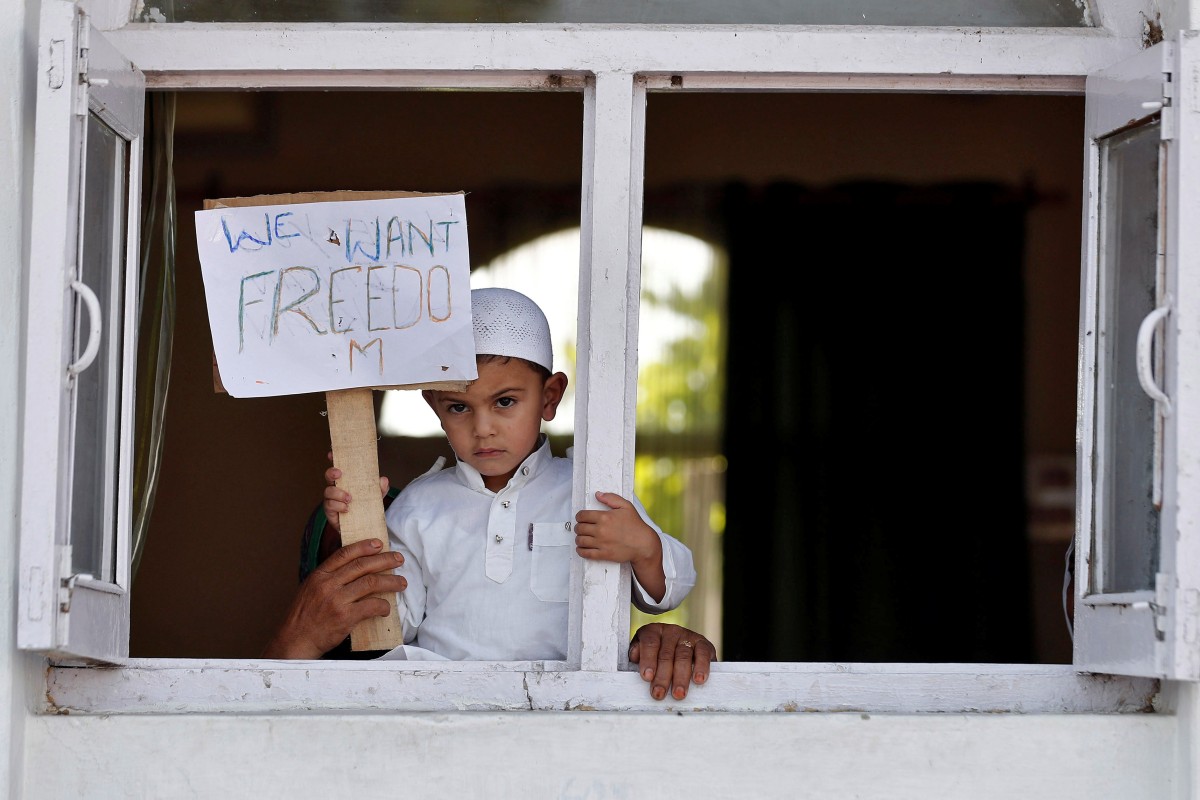 A Kashmiri boy displays a placard from a window at a protest site after Friday prayers. Photo: Reuters