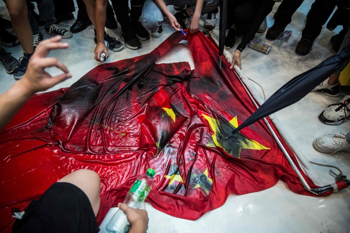 Hard-core demonstrators attack the Chinese flag during violent unrest at New Town Plaza shopping centre in Sha Tin on Sunday, provoking an angry response from state media. Photo: AFP