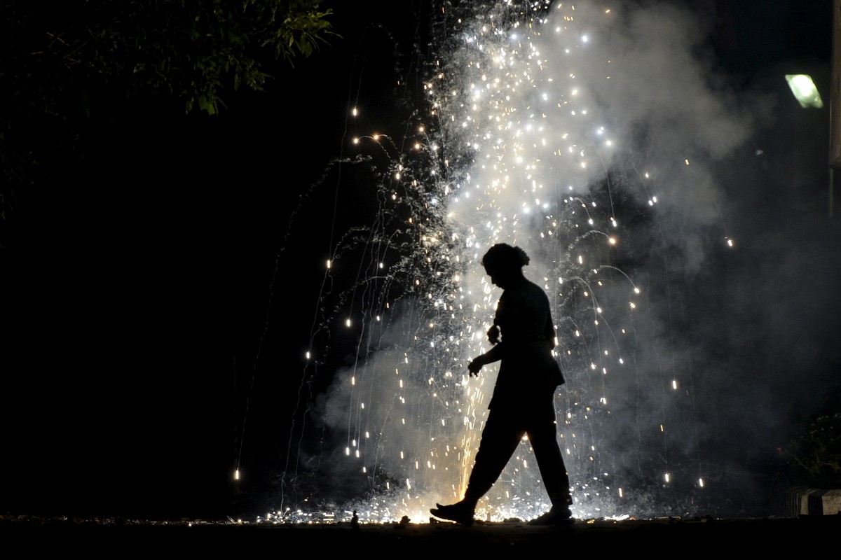 A woman is silhouetted by lit firecrackers during Diwali celebrations in Chennai. Photo: AFP
