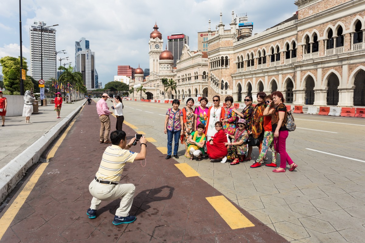 A group of Chinese tourists pose for a photograph in front of the Sultan Abdul Samad Building, in Kuala Lumpur, Malaysia. Photo: Shutterstock