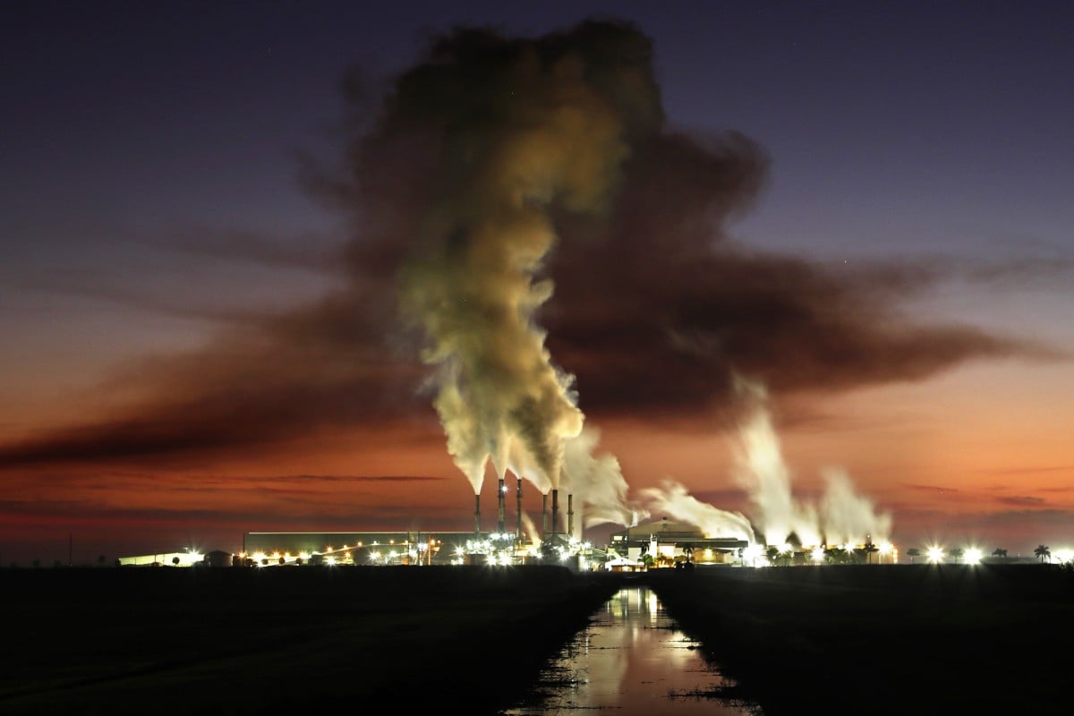 In this Friday, Nov. 1, 2019 photo, the Sugar Cane Cooperative's mill processes sugar cane at dawn in Belle Glade, Fla. The mill operates 24-hours a day during the harvest season, grinding as much as 26,000 tons of sugarcane per day. (AP Photo/Robert F. Bukaty)