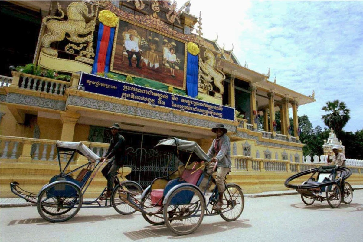 Cyclo drivers pedalling past a portrait of Cambodia’s King Norodom Sihanouk and his wife Queen Monineath displayed at the royal palace in Phnom Penh in 1996. Photo: Reuters