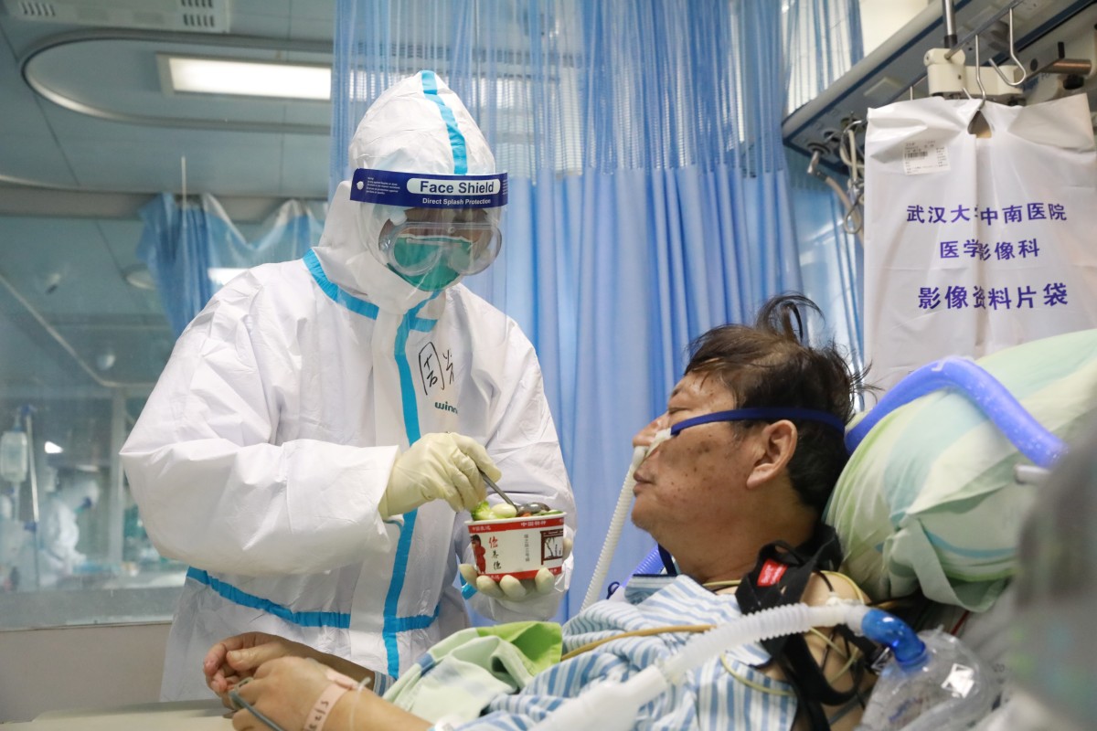 A nurse in a protective suit feeds a coronavirus patient in an isolated ward in Wuhan. Photo: Reuters