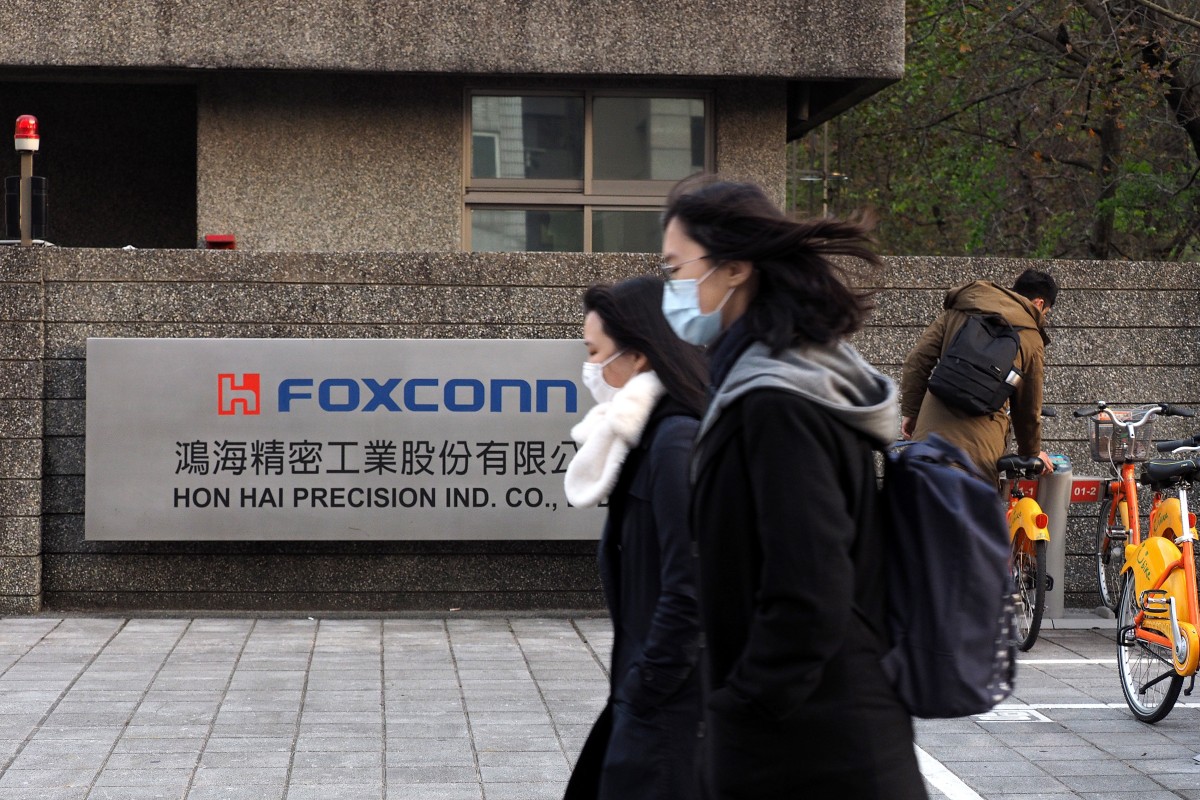 People wearing face masks walk past the logo of Foxconn, the world’s largest contract electronics maker, in New Taipei City, Taiwan. Asia’s emerging markets are most at risk from the fallout of the coronavirus outbreak due to their strong trade linkages with China. Photo: EPA-EFE