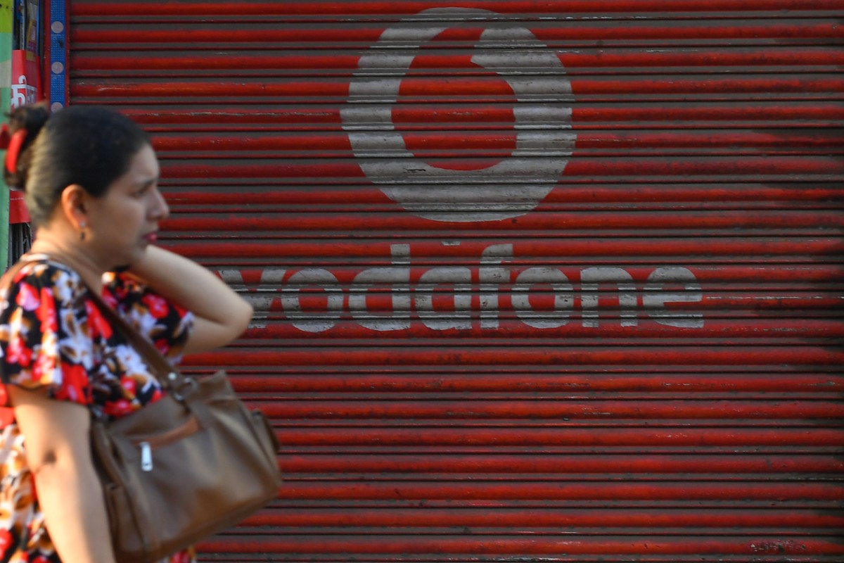 A pedestrian walks past a shop advertising telecoms company Vodafone Idea, which is on the brink of collapse because of accumulated debt and after a ruling by the Indian Supreme Court that telecoms companies must pay billions in unpaid licensing and spectrum fees. Photo: AFP