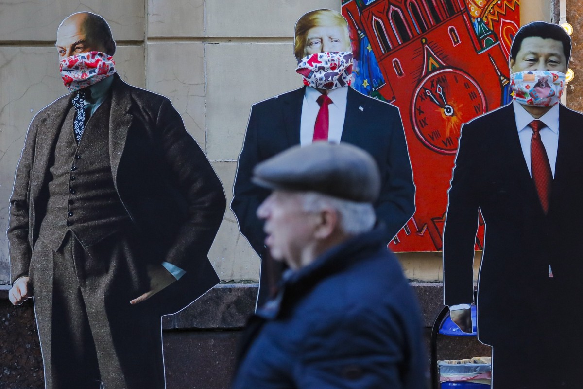 A man passes cardboard figures of Soviet Union founder Vladimir Lenin, US President Donald Trump and Chinese President Xi Jinping wearing face masks near a souvenir shop in Moscow. The three countries will be instrumental in shaping the post-coronavirus world. Photo: EPA-EFE