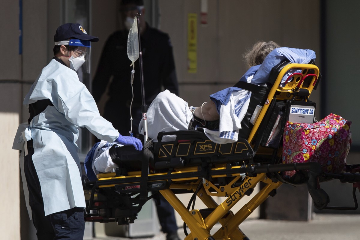 A British Columbia Ambulance Service employee in protective equipment moves a patient from an ambulance to the emergency department at Royal Columbian Hospital in New Westminster, BC, on Sunday. Photo: AP