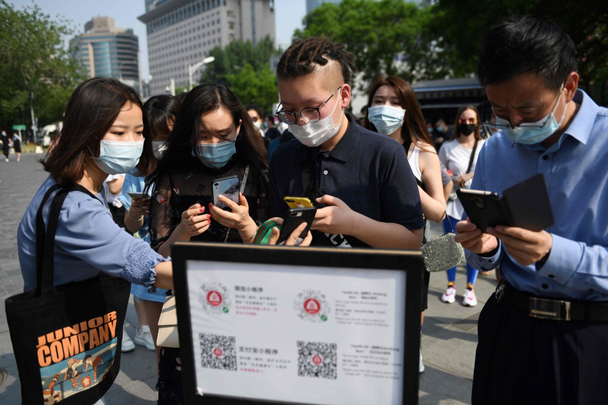 People wear face masks as a preventive measure against the Covid-19 coronavirus as they use a phone app to scan a code required to prove their health and travel status before being allowed to enter a shopping mall, in Beijing on May 2. Photo: AFP
