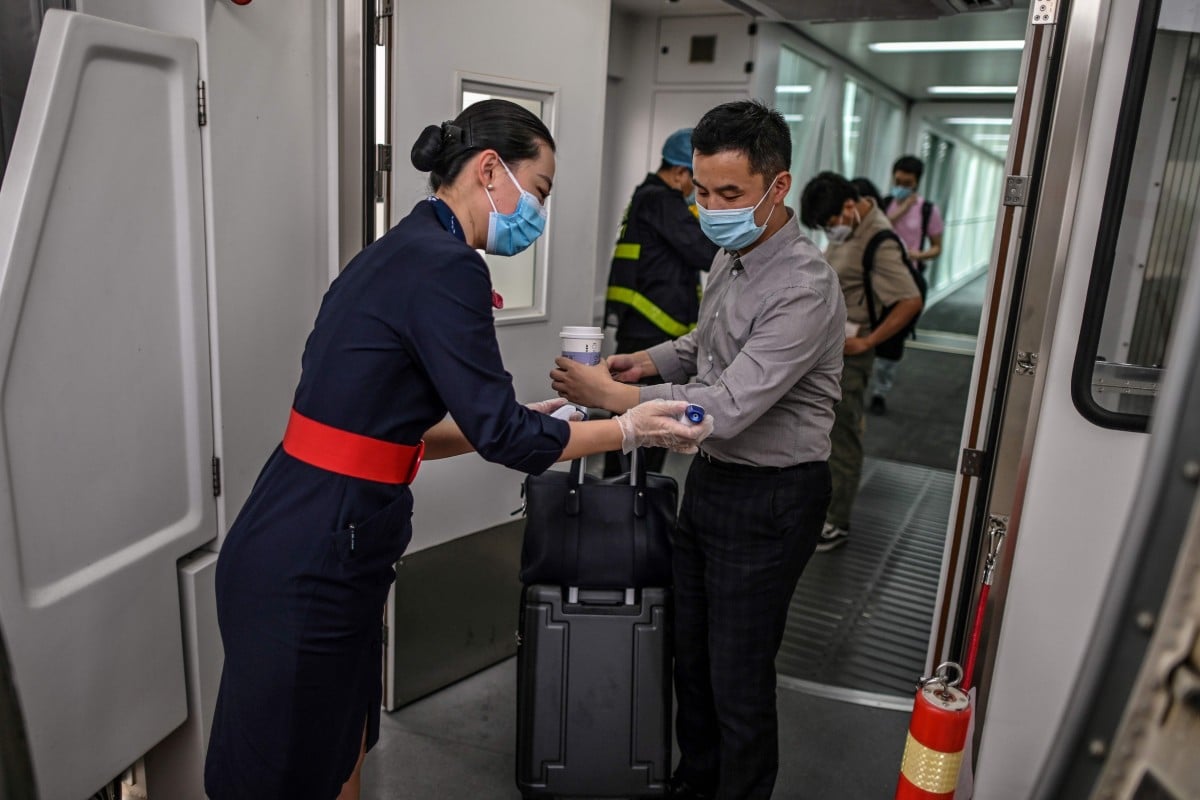 A flight attendant wearing a face mask checks the body temperature of boarding passengers on a plane at Tianhe Airport in Wuhan, China. Photo: AFP