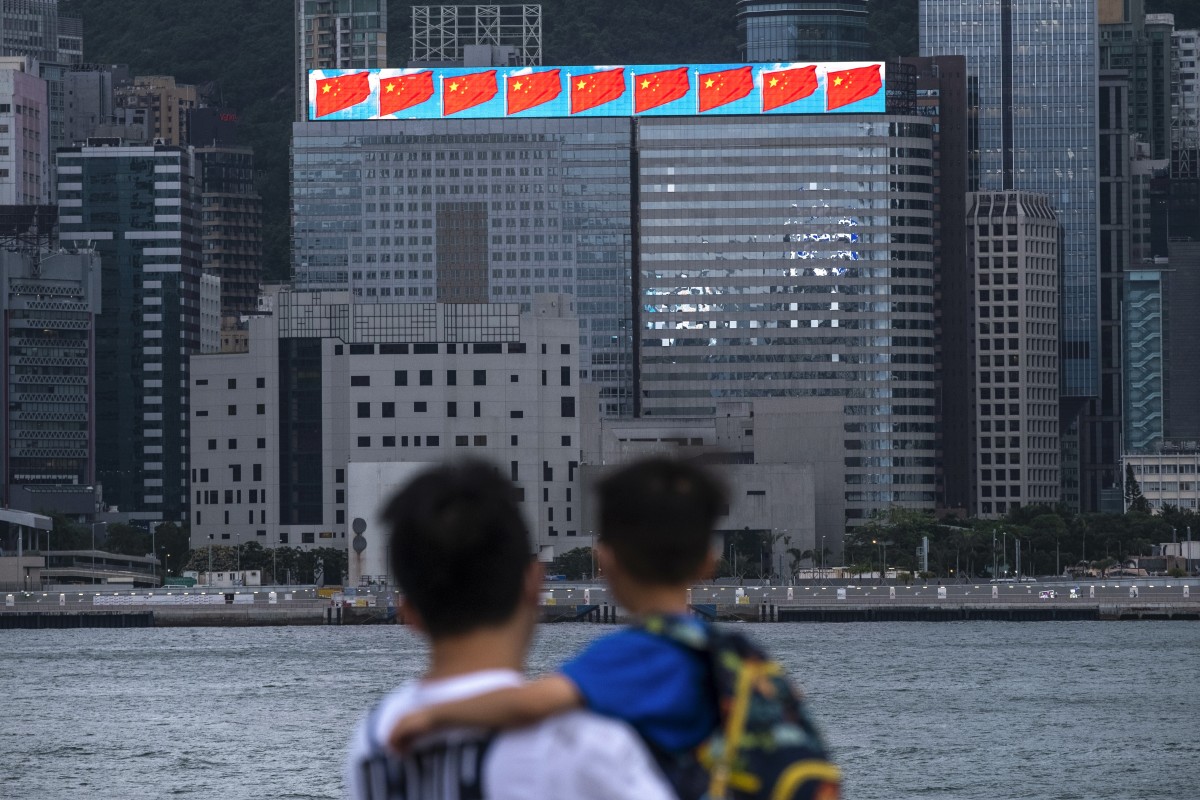 A man and child gaze across Victoria Harbour towards a building with an electronic screen displaying Chinese flags on June 1. Photo: Sun Yeung