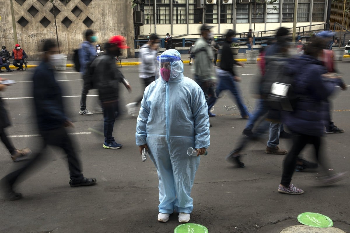 A woman waits outside a shop wearing protective gear due to the Covid-19 pandemic in downtown Lima, Peru on Monday. Photo: AP