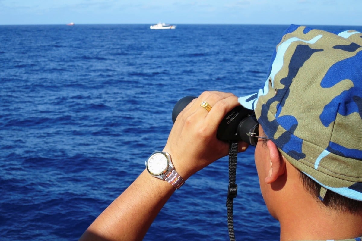 A crewman from a Vietnamese coastguard ship looks out at Chinese military vessels in the South China Sea in 2014. The countries’ disputes over the waterway go back decades. Photo: Reuters