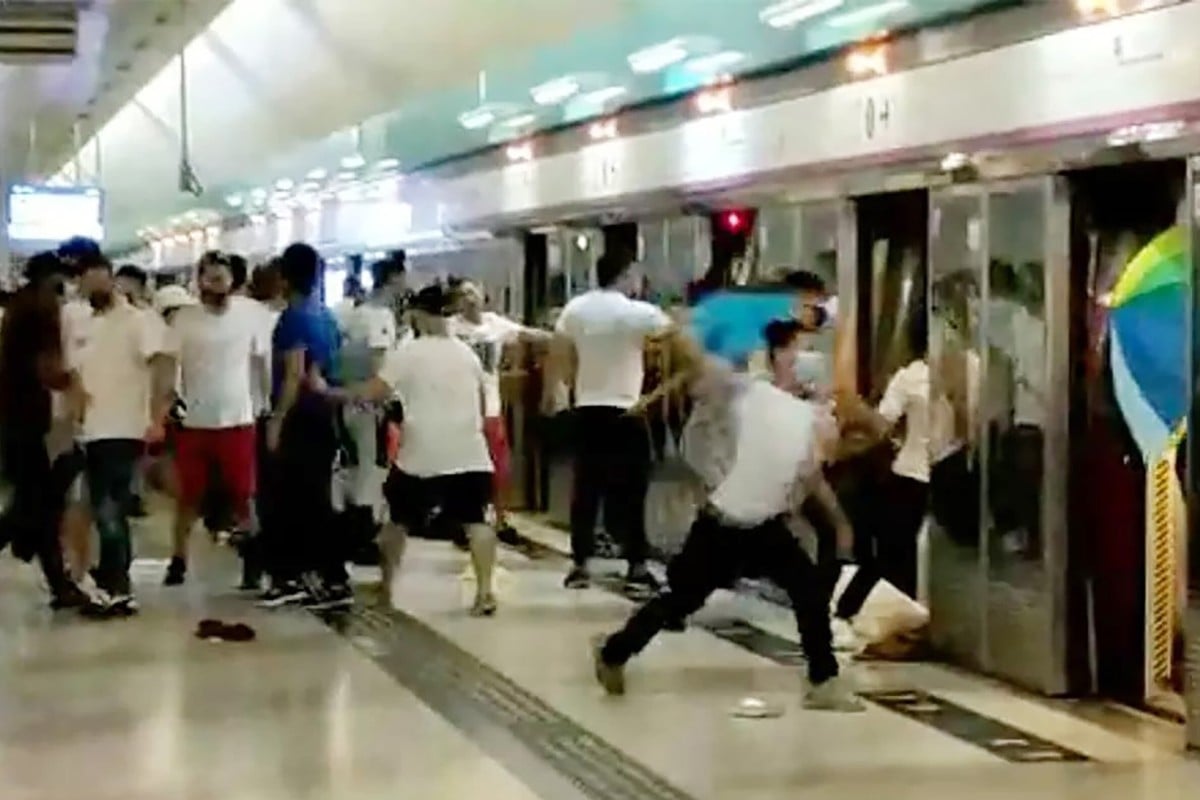 Screen capture from a video showing a number of people in white T-shirts carrying wooden sticks chasing and assaulting passengers arriving at Yuen Long station. Photo: SCMP
