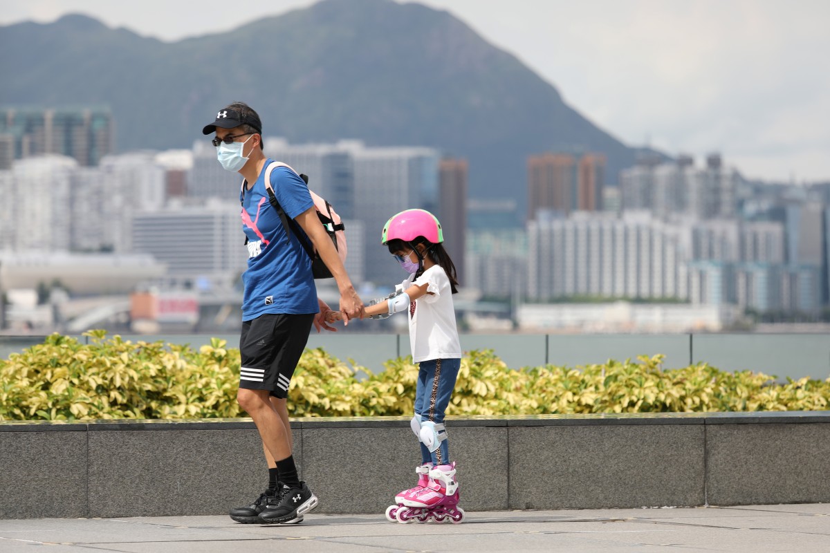 A man pulls along a girl on rollerblades at Tamar Park in Admiralty, Hong Kong, on August 10. Hong Kong has relaxed measures to contain the spread of Covid-19, but some restrictions remain. Photo: Nora Tam