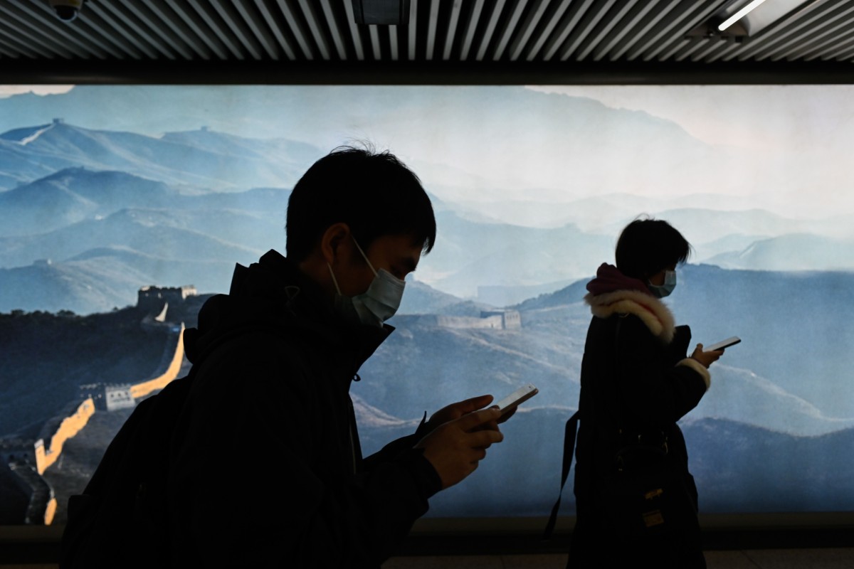 A man and a woman use their mobile phone as they walk in a subway station in Beijing on March 11, 2020. Photo: AFP