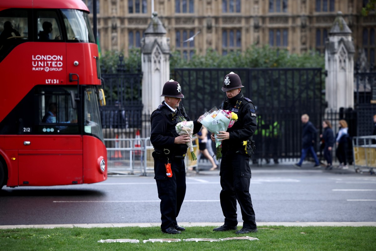 Police officers remove floral tributes that have been laid in Parliament Square, in London. Photo: Reuters
