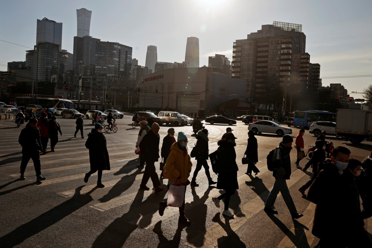 People cross a street during morning rush hour in front of the skyline of the central business district in Beijing in December 2020. Photo: Reuters
