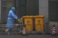 Staff move bio-waste containers past the entrance of the Wuhan Medical Treatment Centre in China, where some people infected with the new virus are being treated. Photo: AP