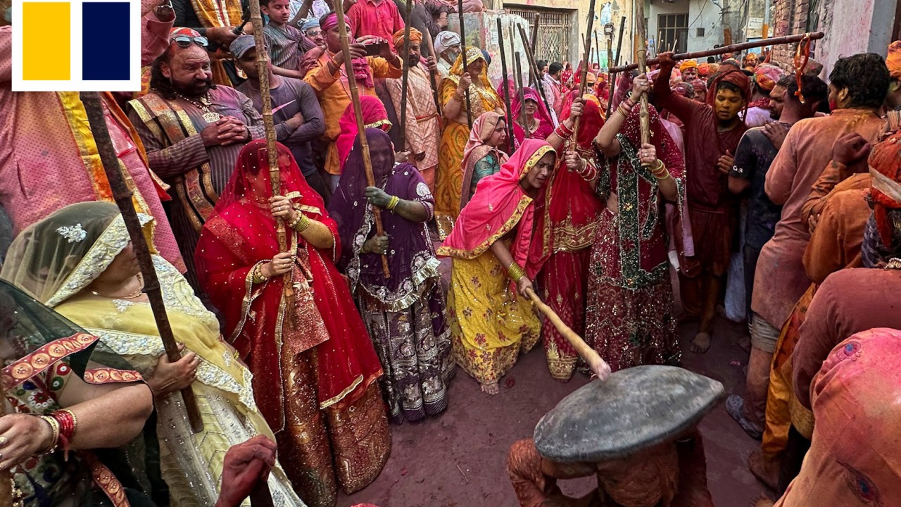 Hindu women in India playfully beat men with sticks during traditional Holi celebrations