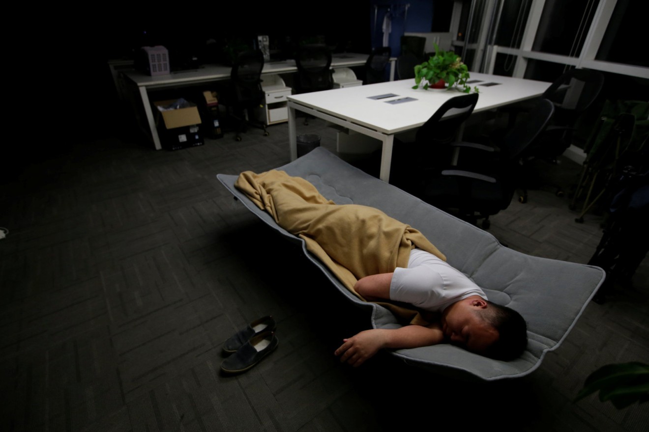 A system engineer in Beijing sleeps on a camp bed at the office after finishing work in the early morning on April 27, 2016. (Picture: Jason Lee/Reuters)