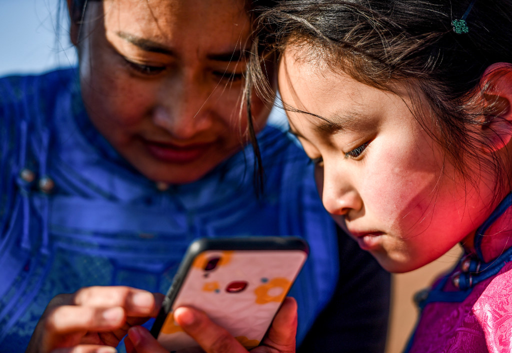 A child in China’s Inner Mongolia Autonomous Region prepares to take online classes with her mother's help (Picture: Lian Zhen/Xinhua)