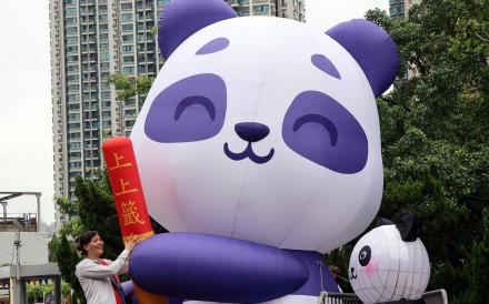 Hong Kong is in the throes of panda fever. A woman takes a photo with a blow-up panda doll in Wong Tai Sin Temple Square, ahead of the arrival of a pair of the bamboo-eating bears from Beijing. Photo: Jelly Tse