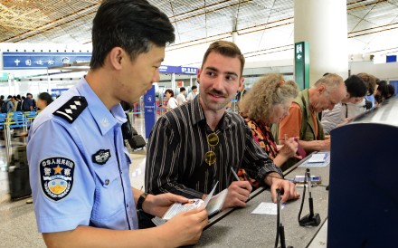 A police officer helps a traveller fill out an entry registration card at Beijing Capital International Airport, on July 10. Photo: Xinhua