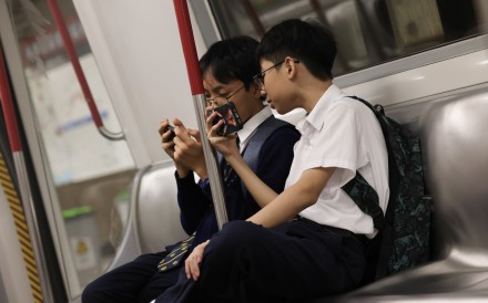 Students use mobile phones on the MTR on June 27. Mainland China has limited online gaming for minors. Australia is banning phones in schools and restricting social media for under-16s. Hong Kong should also act. Photo: Jelly Tse