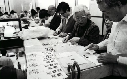 Eager philatelists in Hong Kong carefully stick a set of stamps onto first-day covers inside a post office in 1986. The stamps were issued to commemorate the Queen’s 60th birthday. Photo: SCMP Archives