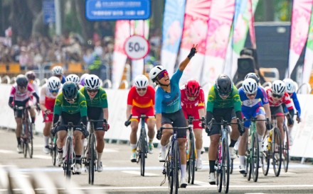 Ceci Lee (centre) raises her arm in victory after her road race gold medal win in Zhuhai. Photo: Eugene Lee