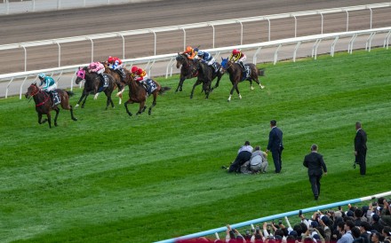 Jockey Club officials hold a man who ran onto the track down during Sunday’s Hong Kong Cup at Sha Tin. Photos: Kenneth Chan