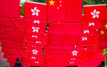 A worker installs Chinese national and Hong Kong special administrative region flags in Tsim Sha Tsui, ahead of the 29th anniversary of Hong Kong’s return to the motherland on June 25. Photo: Jelly Tse