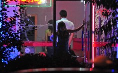 A woman stands in the doorway of a neon-lit “barber shop” in Beijing in July 2008. Some sex workers operate from stores like these, which have nothing to do with haircuts. Photo: AFP