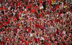 Spectators wave the Singapore national flag as they wait for the start of the 54th national day parade on Friday. Photo: AFP