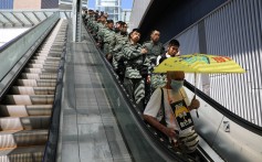 A line of police officers ride an escalator at the Legislative Council on October 16, behind a protester holding an umbrella. Photo: Reuters