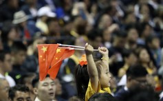 A child holds up two Chinese national flags as she watches a preseason NBA game between the Brooklyn Nets and Los Angeles Lakers in Shanghai, China. Photo: AP