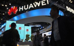 Attendees walk past the booth of Huawei Technologies at the PT Expo China trade show in Beijing on October 31. Photo: AP