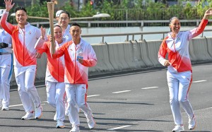 Jockey Vincent Ho carries torch during the National Games relay on Sunday morning. Photo: HKJC