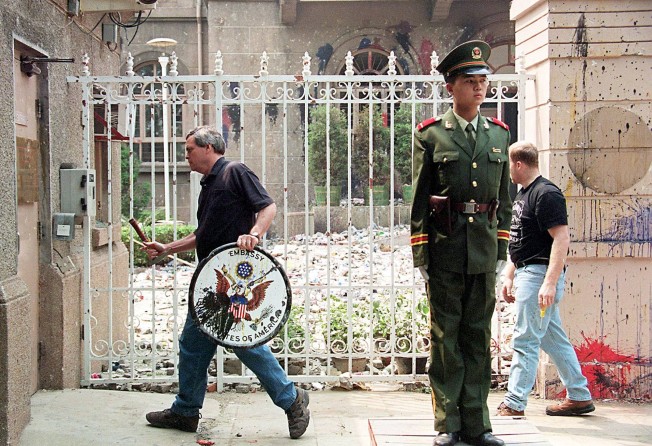 US embassy staff remove the plaque at the embassy’s main gate in Beijing on May 12, 1999. Photo: AFP