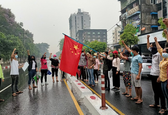 Anti-coup protesters hold a Chinese flag before burning it down in Yangon. File photo: Reuters