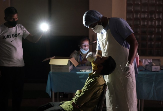 A health worker takes a swab under mobile phone torchlight during a power cut at a temporary Covid-19 testing site in New Delhi, India. Photo: Bloomberg