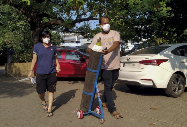 A couple walks with an oxygen cylinder for a Covid-19 coronavirus patient in Goa. Photo: AFP