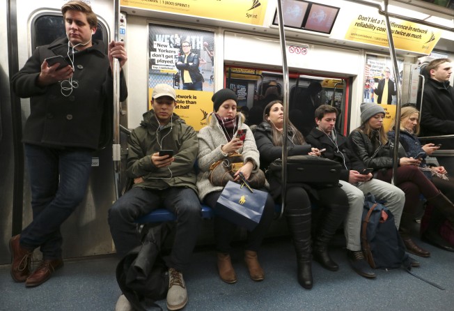 Commuters wearing headphones on a train in New York. Researchers have found that even just a 30-second exchange with a stranger can make us feel significantly less lonely. Photo: Getty Images
