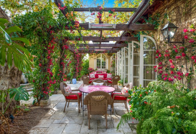 Outside, pink accents on the garden furniture echo the blooms overhead on the pergola. Photo: Anthony Barcelo