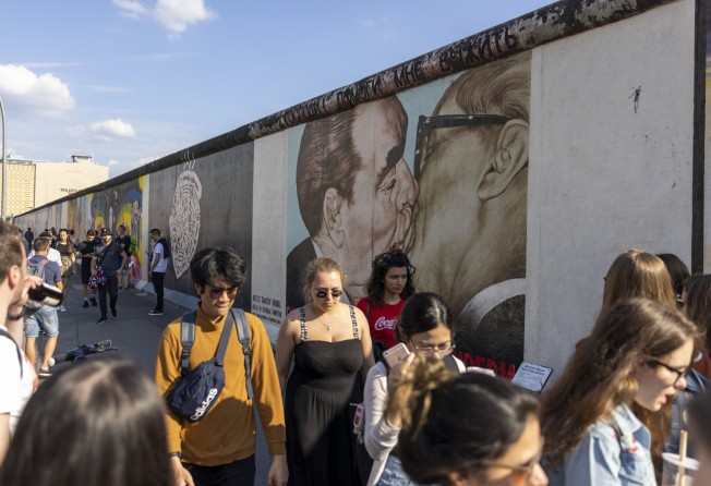 Visitors walk past a mural showing former Soviet leader Leonid Brezhnev kissing ex-East German President Erich Honecker at the East Side Gallery in Berlin. Photo: Getty Images