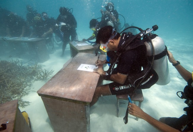 Then Maldivian president Mohammed Nasheed signs a document on October 17, 2009, calling on all countries to cut their carbon dioxide emissions, at an underwater event in Girifushi, Maldives. Photo: AP